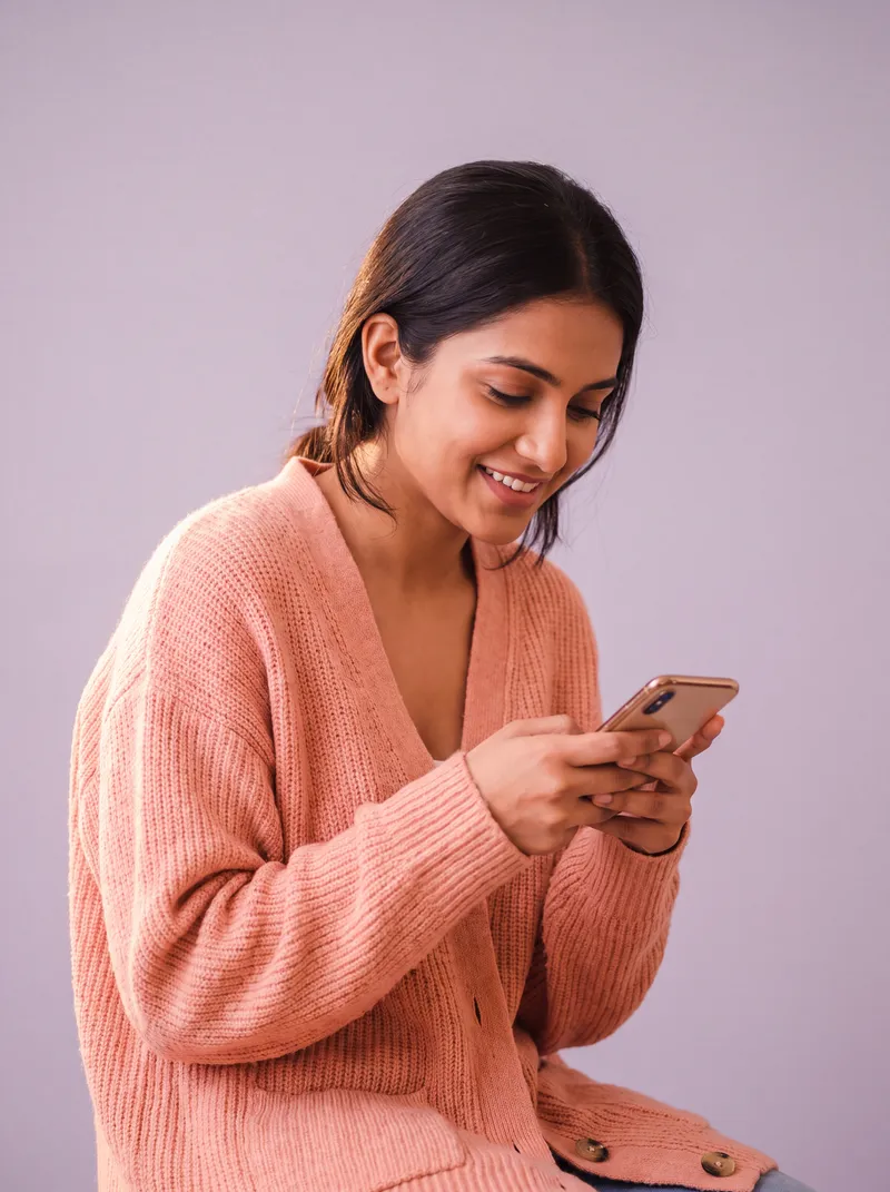 A young woman smiling to herself at her phone.